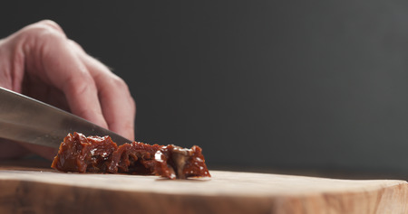 closeup man slicing sundried tomatoesの写真素材