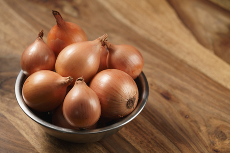 brown onions on old wood table, shallow focusの写真素材