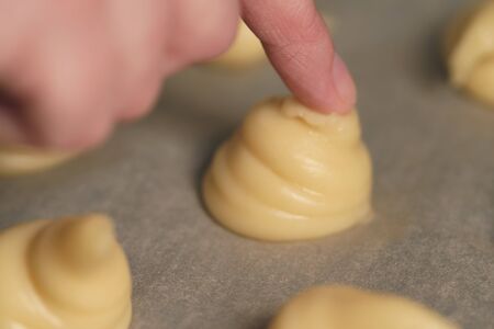 tipping choux dough for profiteroles on baking paperの写真素材