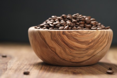 roasted coffee beans in wood bowl on table with dark backgroundの写真素材