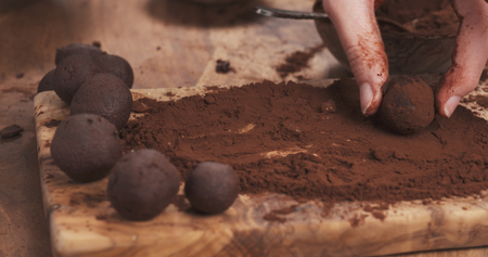 female hands making truffles in cocoa powder on boardの写真素材