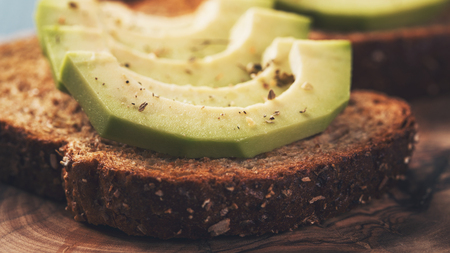toasted rye bread with sliced avocado and herbsの写真素材