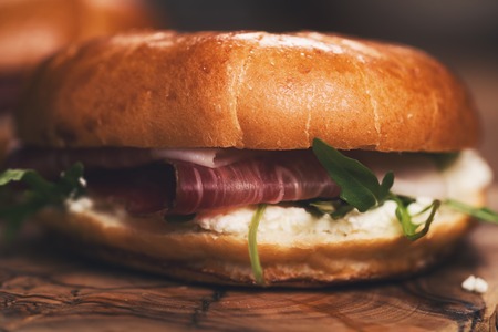 two bagels with prosciutto and cream cheese on wood boarの写真素材