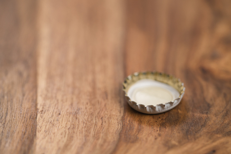single white beer bottle cap on wood tableの写真素材