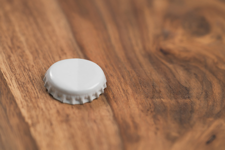 single white beer bottle cap on wood tableの写真素材