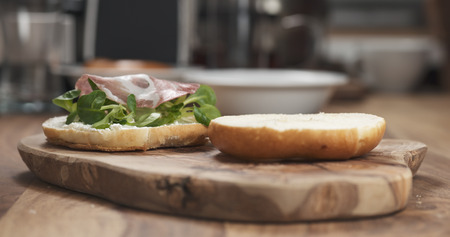 bagel sandwich with coppa and cream cheese on wood boardの写真素材