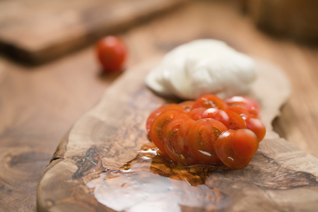 sliced cherry tomatoes and mozzarella on wooden boardの写真素材