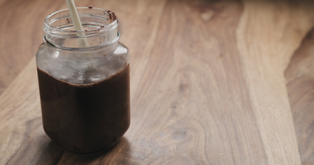 making cocoa drink in glass jar with handle on wood table, milk pourの写真素材