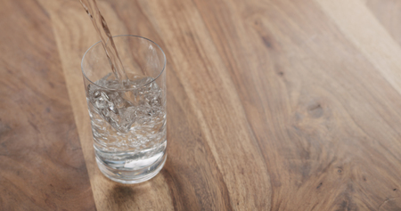pouring water in glass on wood tableの写真素材