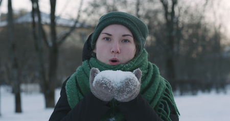 closeup of teen girl blowing snow from hands on cold winter dayの写真素材