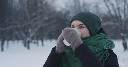teenage girl drinking hot cocoa in park on a winter day
