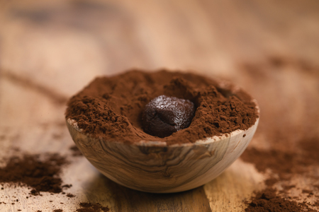 chocolate truffle in cacao powder in wood bowl on table, shallow focusの写真素材