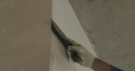 worker applying putty on the wall near cornerの写真素材