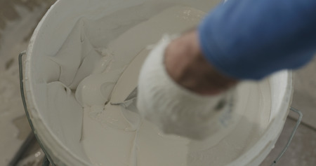 worker take white putty ready to apply from a bucketの写真素材