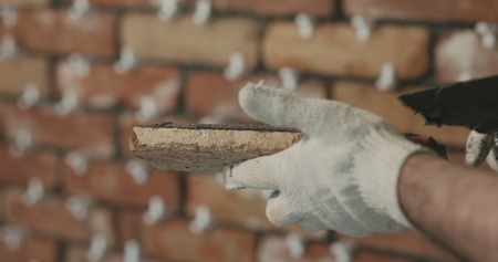 closeup worker applying concrete glue to brick tileの写真素材