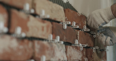 closeup worker applying brick cuts tile to the wallの写真素材