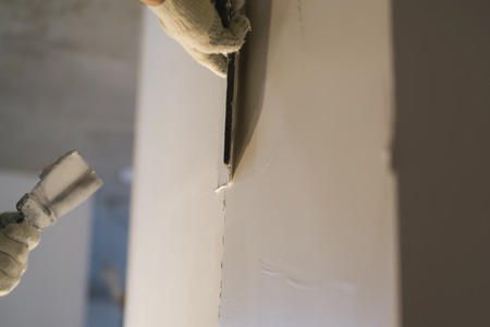 worker applying putty on the wall with putty knife, shallow focusの写真素材