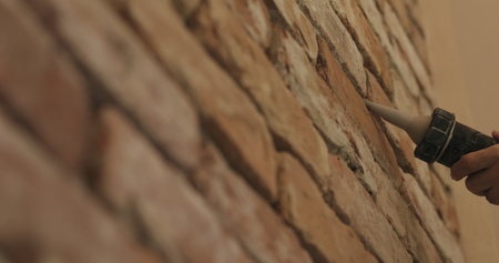 Slow motion closeup of worker filling seam between bricks with mortar from sealant gunの写真素材