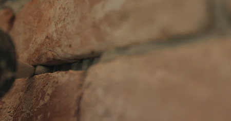 Slow motion closeup of worker filling seam between bricks with mortar from sealant gunの写真素材