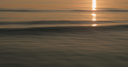 closeup small waves on a beach at sunsetの写真素材
