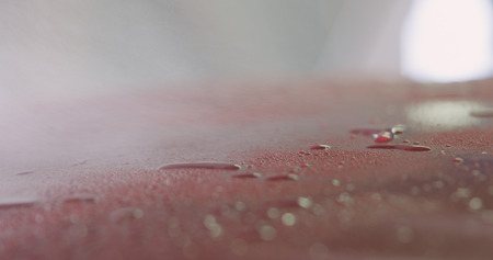 Closeup red car wash spraying degreaser on paintの写真素材