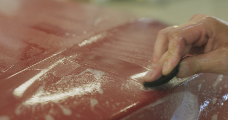 professional applying protective film to the red car