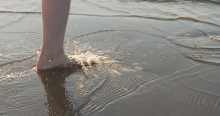 Close-up young female legs running on the beach, wide photoの写真素材