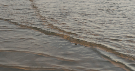 Closeup of small waves on a beach at sunset, wide photoの写真素材