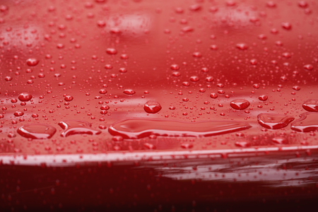 Closeup rain drops on red car with hydrophobic coatingの写真素材