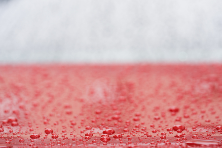 Closeup rain drops on red car with hydrophobic coatingの写真素材