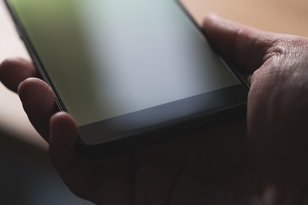 young man hand hold smartphone close-up, shallow focus