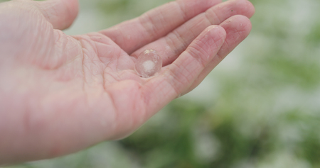 closeup pov male hand holding hailstones after hailstormの写真素材