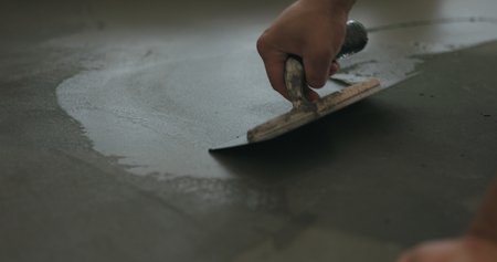 closeup worker applying micro concrete on the floor with a trowelの写真素材