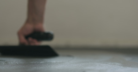 closeup worker applying micro concrete on the floor with a trowel
