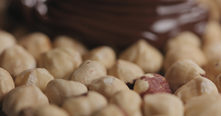 closeup covering roasted hazelnuts with melted dark chocolateの写真素材