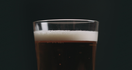 Closeup light ale beer with bubbles over black backgroundの写真素材