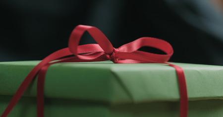 Macro red ribbon bow on green gift box