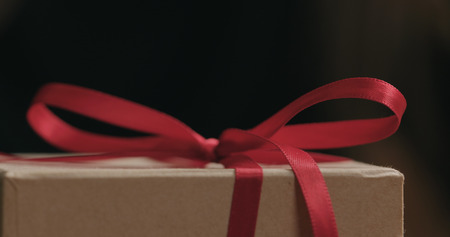Macro red ribbon bow on craft gift box, wide photoの写真素材
