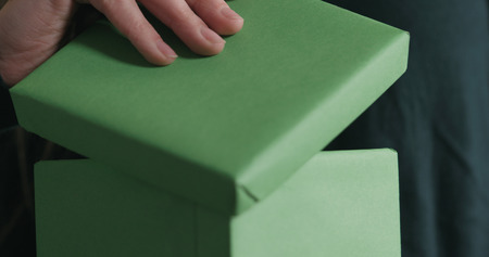closeup shot of young female hands opens green paper gift box, wide photoの写真素材