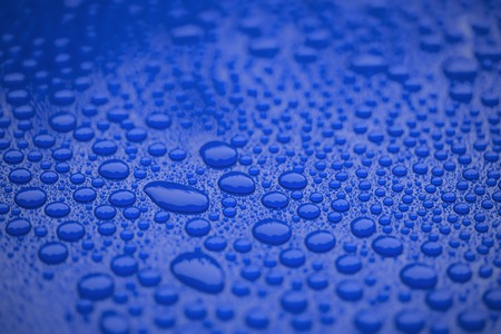 Closeup waterdrops on blue ceramic coated paint surface, shallow focusの写真素材