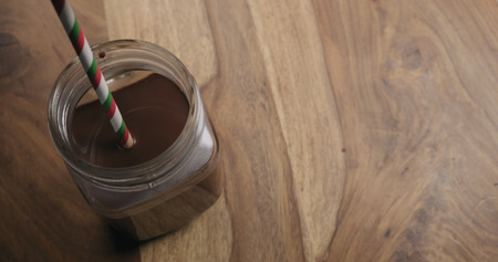 cocoa with christmas striped paper straw in glass jar on wood background with copy space shot from above, wide photoの写真素材