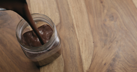 pour hot cocoa in glass jar on wood background with copy space, wide photoの写真素材