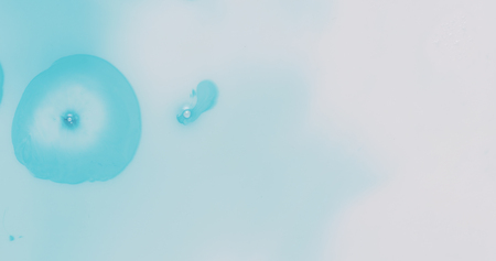 blue ink drops spreads on white plastic background, wide photoの写真素材