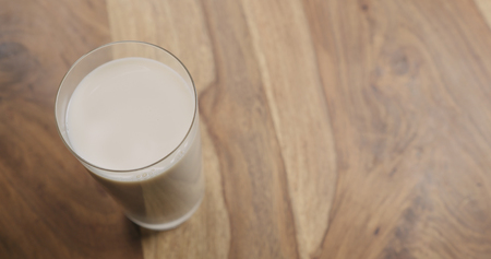 oat milk in glass on wood background with copy space, wide photoの写真素材