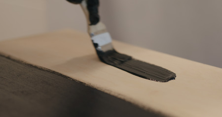 Brush painting plywood with black paint, wide photoの写真素材