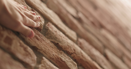 closeup man hand touching old brick wall, wide photo