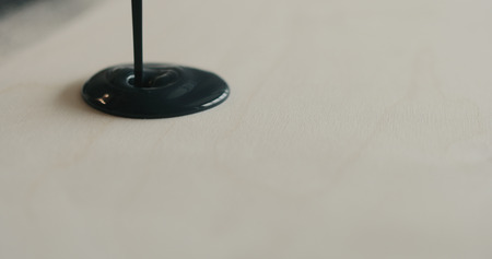 closeup pouring black paint on plywood, wide photoの写真素材