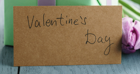 Closeup   of green gift box with purple bow and tulip on blue wood background with valentines day greeting cardの写真素材