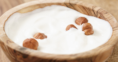 Closeup   of homemade yogurt with hazelnuts in wood bowl on wooden tableの写真素材