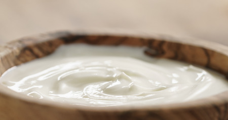 Closeup   of homemade organic yogurt in wooden bowl on tableの写真素材